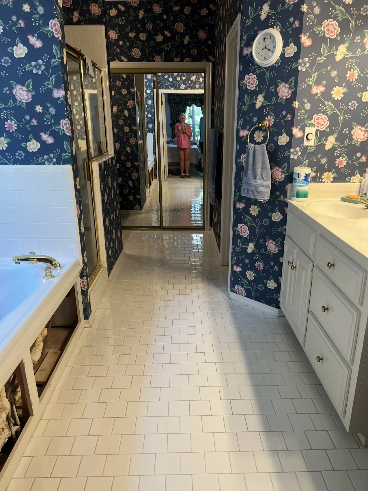 Before: bathroom with floral wallpaper, white floor tile, and gold shower frame