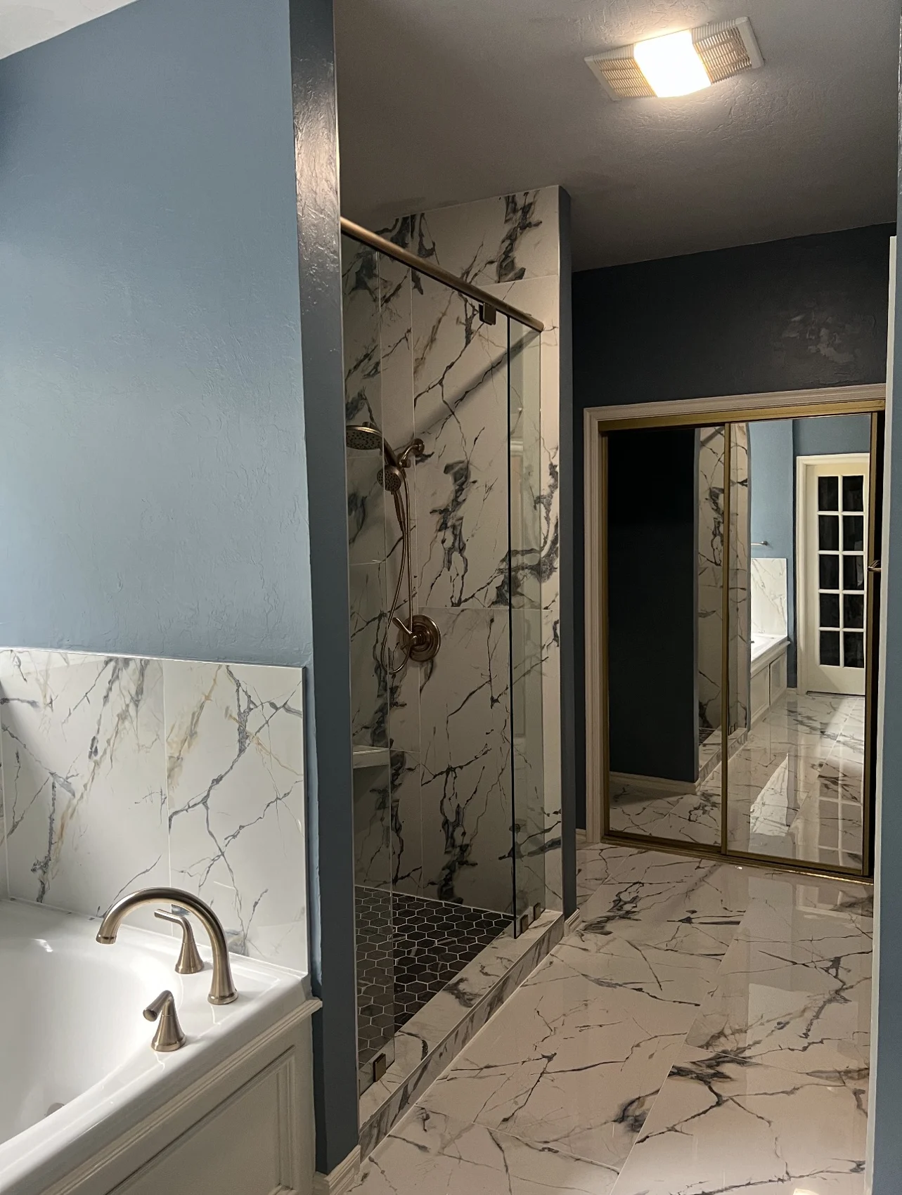 After: bathroom with marble-look floor and shower walls, blue walls and glass shower