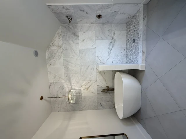Dusty Project freestanding white bathtub beside marble-look tiled walk-in shower
