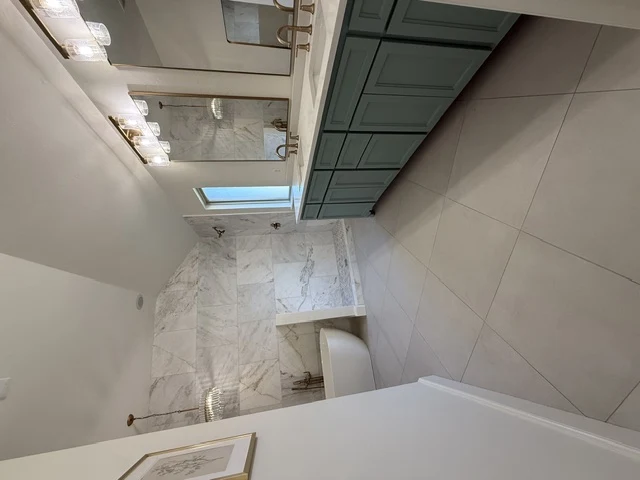 Dusty Project finished bathroom with green double vanity, marble-look shower, freestanding tub and warm metal fixtures